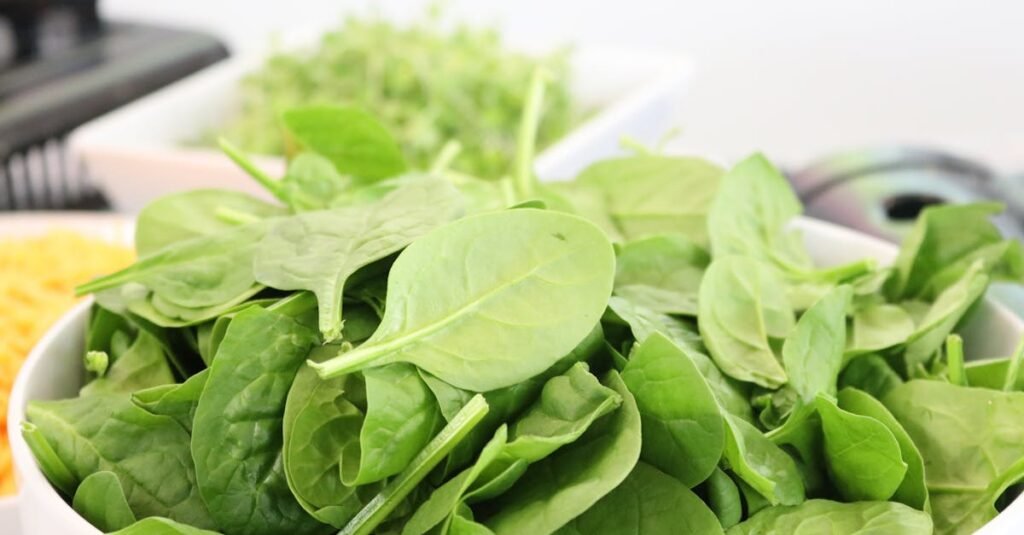 A close-up of fresh spinach leaves in a white bowl, ideal for healthy salads.